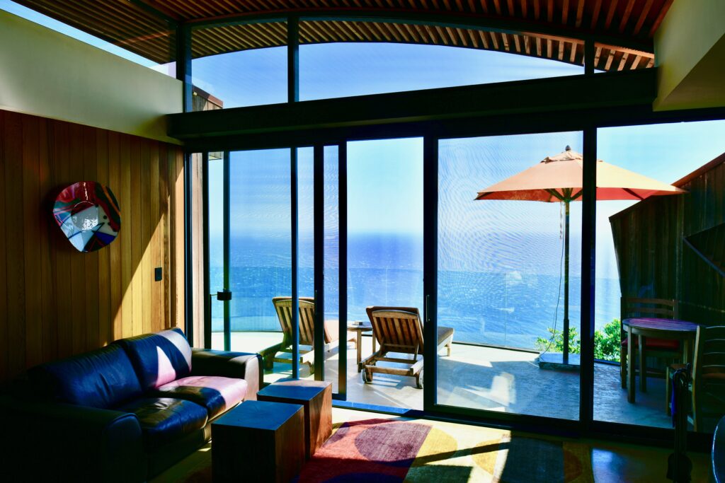A living room with a large window overlooking the ocean.