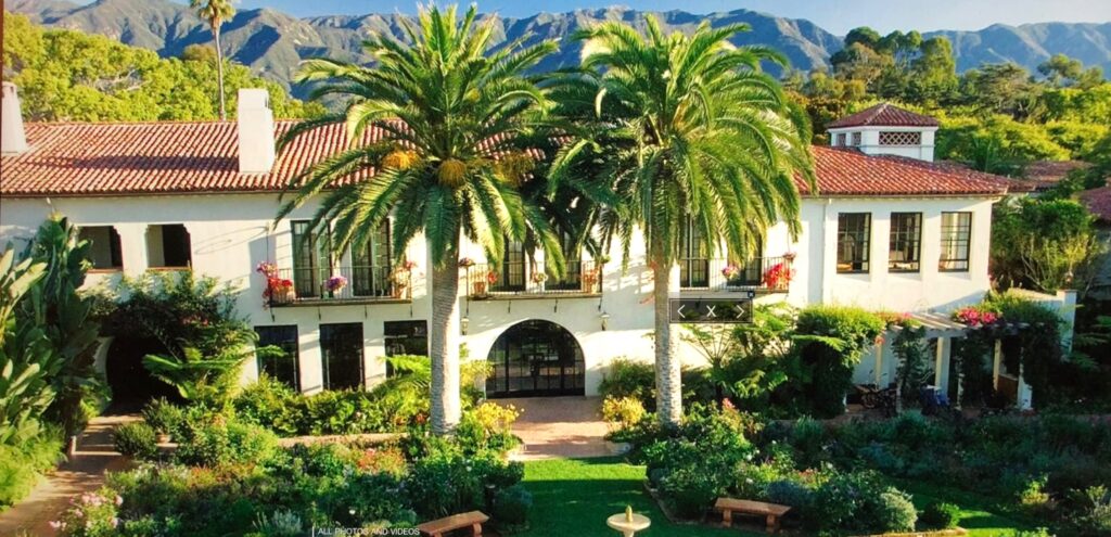 A large white building with palm trees in the center.