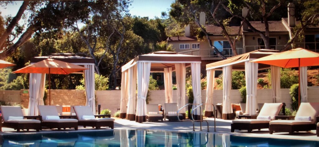 A pool with white curtains and a wooden structure