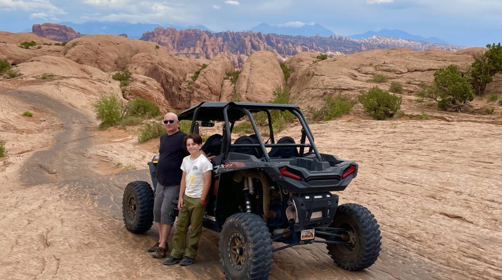 A man and boy standing next to an atv.