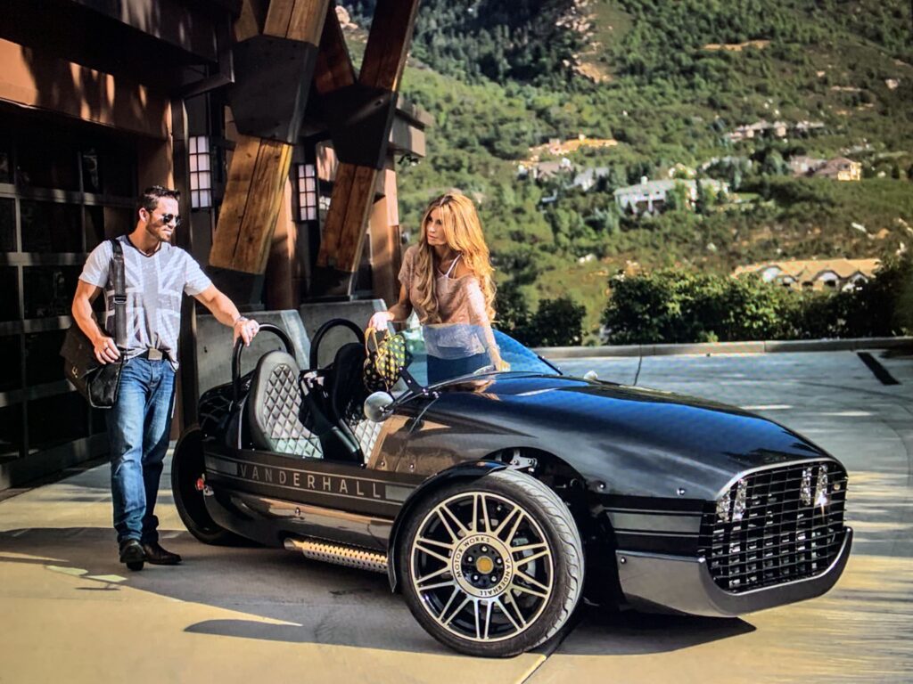 A man and woman standing next to an old car.