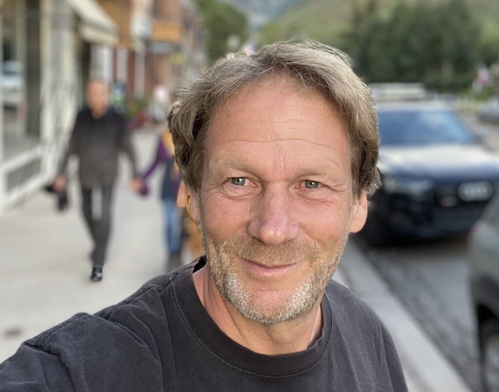 A man with long hair and beard is smiling.