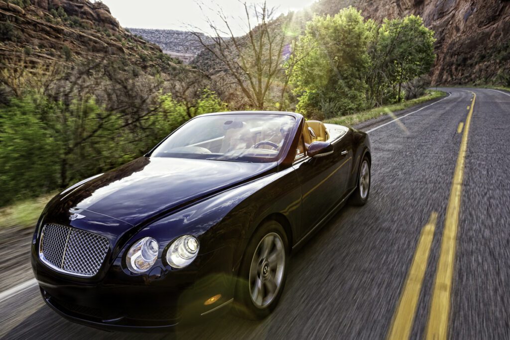 A black convertible car driving down the road.